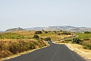 La RD 5 sillonnant les garrigues et vignes d'Opoul, avec la forteresse de Salveterra  l'horizon ( gauche)